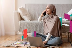 Woman talking on phone with laptop, discussing business setup in UAE.