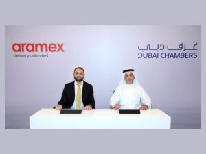 Two men seated at a table with Aramex and Dubai Chambers logos behind them.